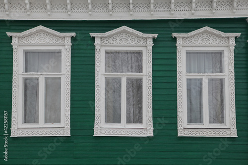 Ornamental carved windows, frames on green traditional national old wooden rural house in Gorodets city, Russia. Russian folk style in architecture. Gorodets architectural monument, Gorodets landmark photo