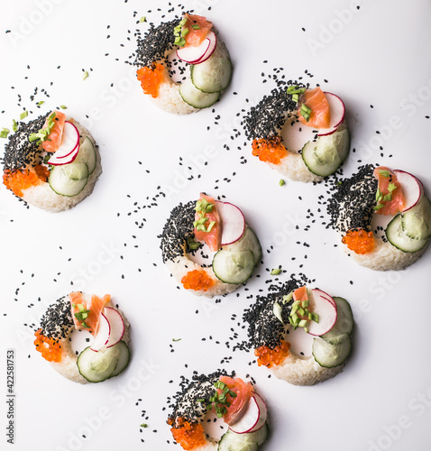 Sushi donuts with salmon, cucumber and radish on white background top view. Hybrid Foods.