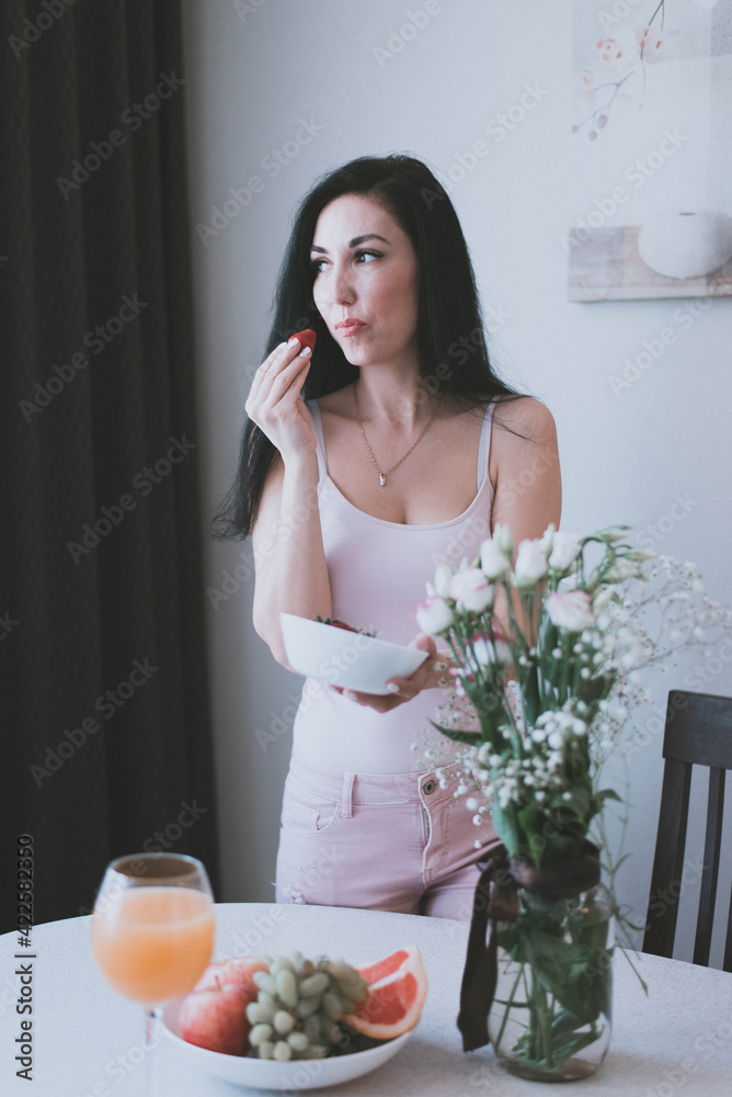 brunette girl eating strawberries from a white plate brunette girl eating strawberries from a white plate
