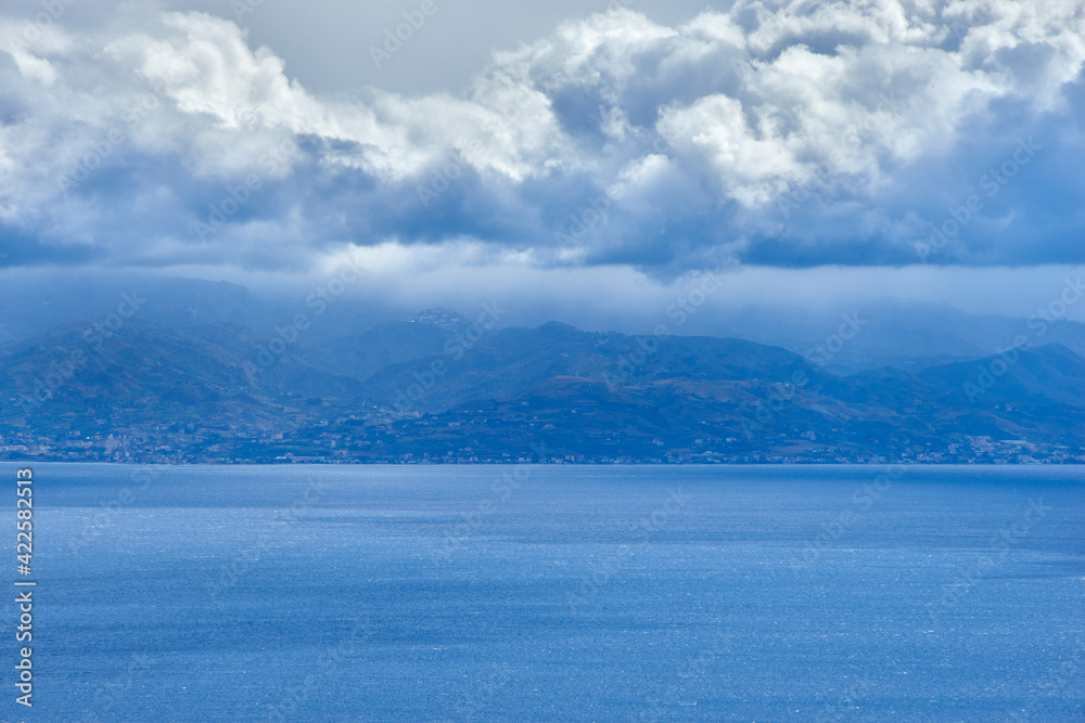 the coast of Calabria seen from the Strait of Messina with big clouds unexpected for a thunderstorm