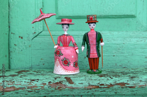 Ancient russian traditional national handicraft, folk art - old wooden toys. Gorodets (gorodetskaya) painting. Retro lady in pink dress with umbrella and her cavalier in hat. Souvenir from Russia photo