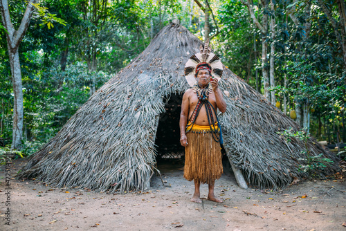 Obraz na plátne Shaman of the Pataxó tribe, wearing feather headdress and smoking a pipe