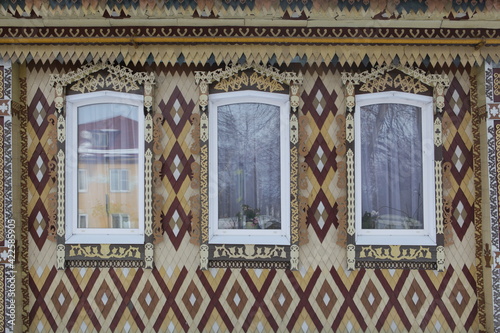 Ornamental carved windows, frames on traditional national old wooden rural house in Gorodets city (Russia). Russian folk style in architecture. Architectural monument, landmark, sight, attraction photo