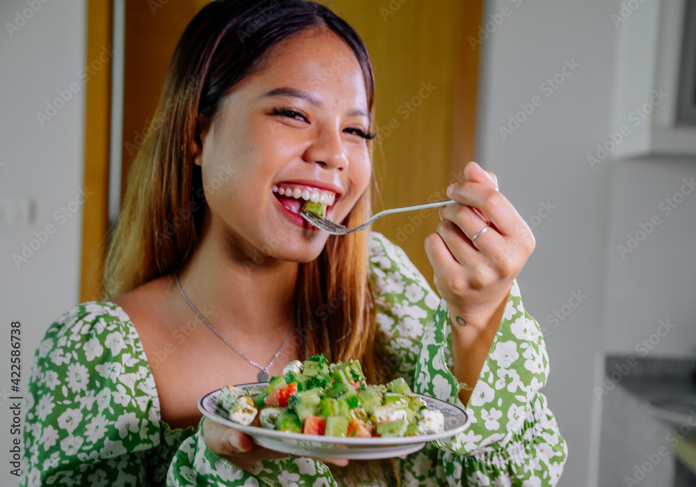 beautiful young asian woman eating healthy mediterranean food. smiling happy girl eating greek salad