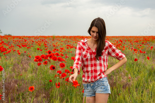 Young beautiful woman on a poppy field, summer outdoor. photo