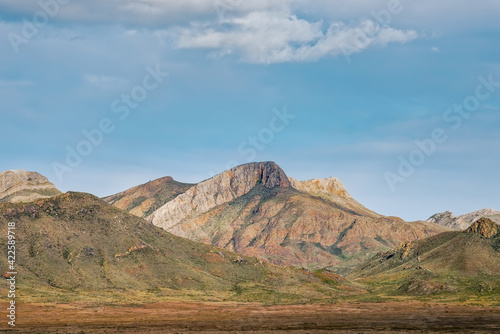 A mountain of unusual texture in the steppes of Tuva, a stone ridge against the background of the sky with clouds