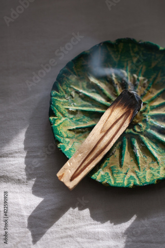 Burning palo santo stick on ceramic plate. Antistress and relaxation ritual concept