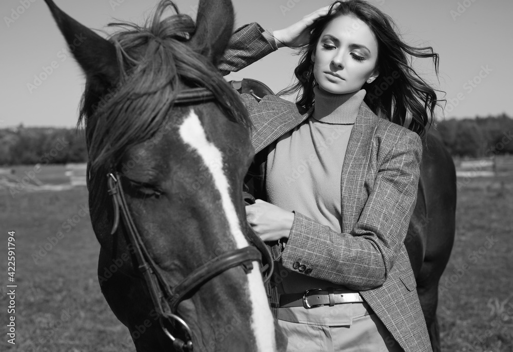Obraz premium Beautiful brunette woman in an elegant checkered jacket with a horse