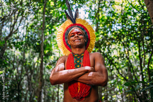 Indian from the Pataxó tribe, with feather headdress. Young Brazilian Indian looking at camera, smiling and arms crossed photo