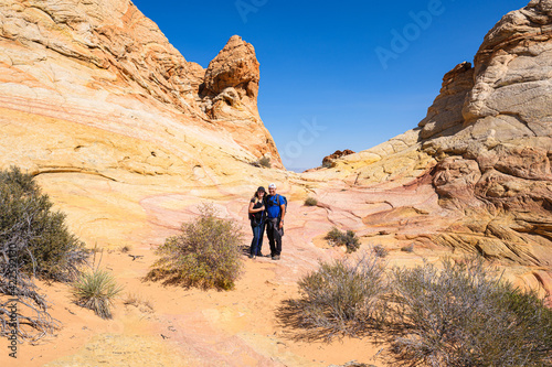 Couple hiking in the beautiful landscape and rock formations of Coyote Buttes South in the Vermilion Cliffs National Monument in northern Arizona