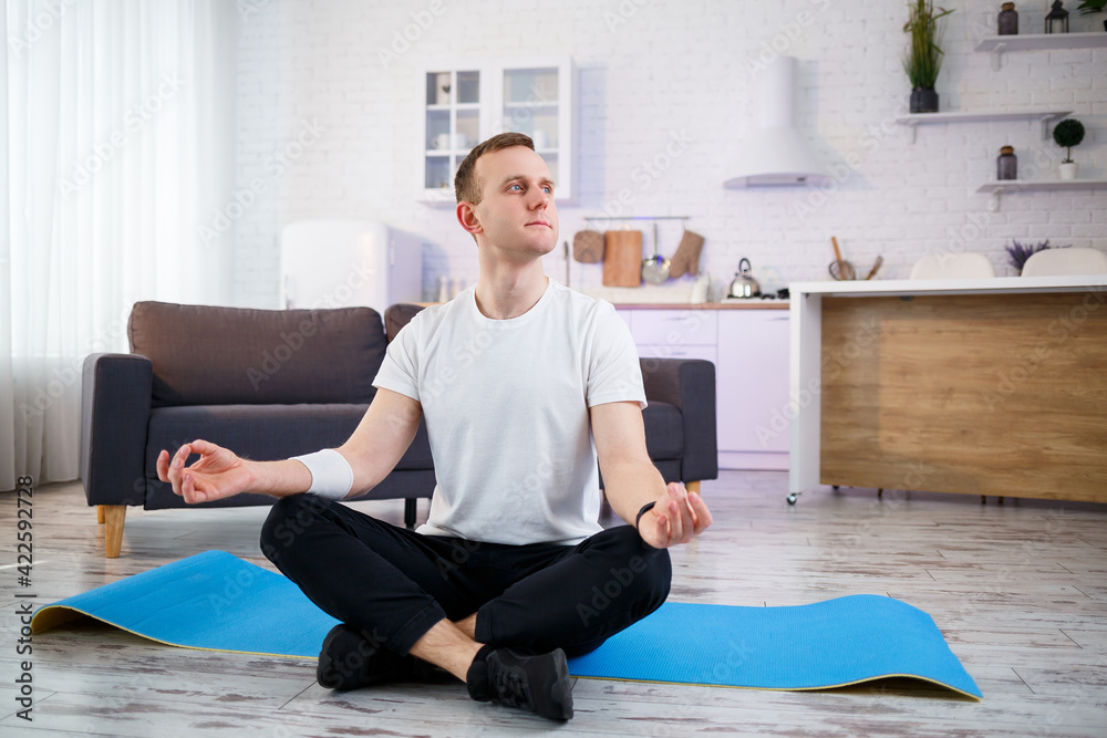 A man doing yoga exercises at home, sitting on the living room floor. Healthy lifestyle. A man doing yoga exercises at home, sitting on the living room floor. Healthy lifestyle.