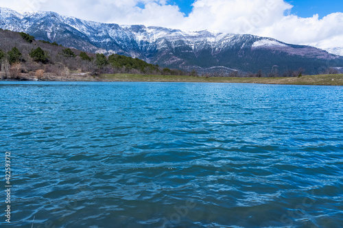 Blue water of a mountain lake and mountains in the distance covered with snow