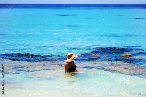 Young woman with straw hat sitting in shallow water