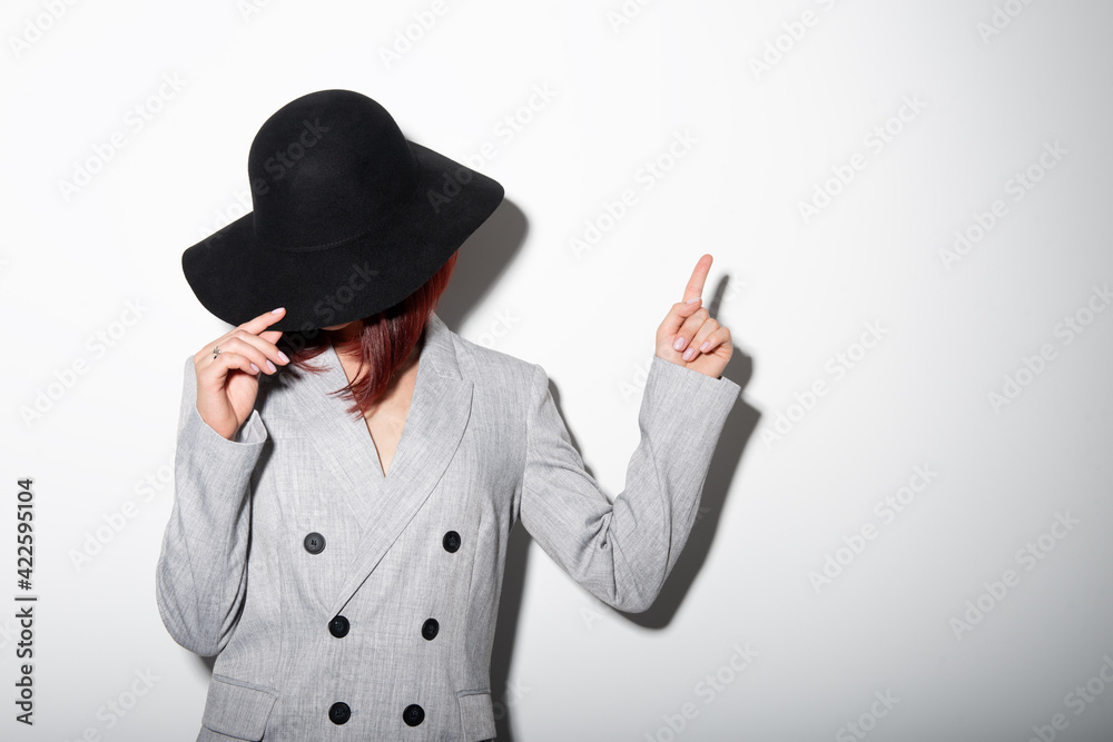 Mysterious fashion young woman in black hat pointing at copy space where can the advertising message be written Mysterious fashion young woman in black hat pointing at copy space where can the advertising message be written