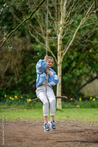 Girl on a stick swing.A young girl smiling while swinging on a stick swing at a park. © carrigphotos