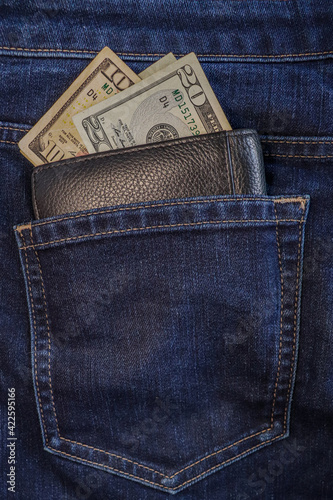 One hundred dollar note in the back pocket of blue jeans. Dollar bills in jeans pocket close-up.