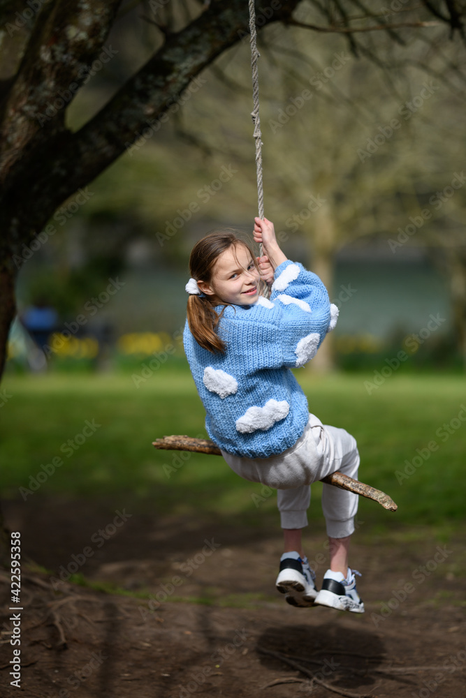 Girl on a stick swing.A young girl smiling while swinging on a stick swing at a park.