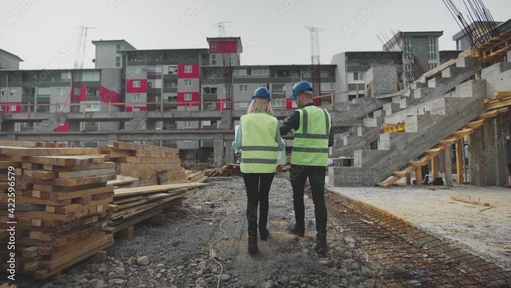 An Engineer and an Architect walking through the ongoing Building site and discussing the project plans. An Engineer and an Architect walking through the ongoing Building site and discussing the project plans.