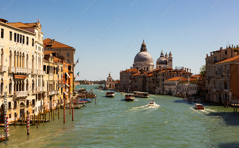 VENICE, ITALY - SEPTEMBER 05, 2019: Scenic view of Grand Canal with old colorful architecture of central districts and Baroque domes of Santa Maria della Salute in sunny day..