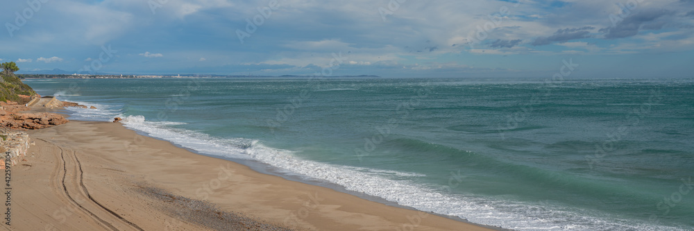 Beautiful beach at Costa Dorada in Miami Platja with a background of blue sky with clouds, Catalonia