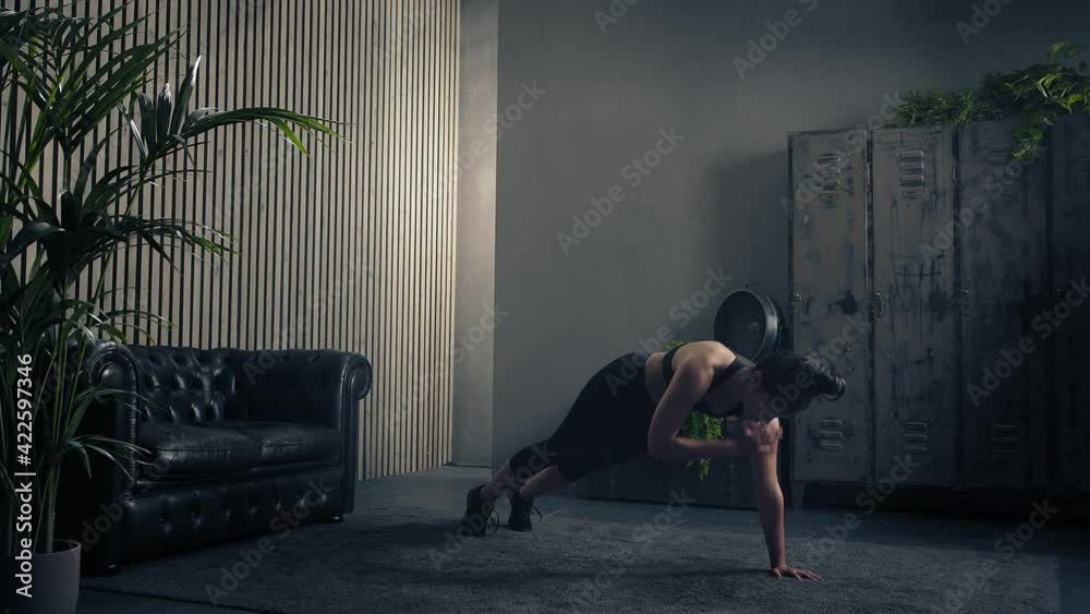 Sporty and beautiful brunette woman doing shoulder tap push ups in sportswear at home. Slow motion
