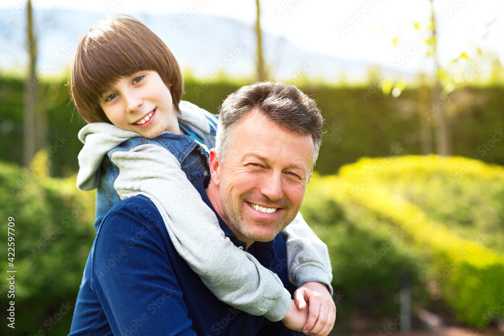 Father with son walking i spring park. Handsome mature man and cute 11 years boy posing over spring outdoor.