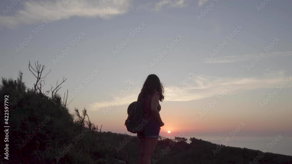 Woman with a backpack in a mountain watching the sunset in the sea. Woman with a backpack in a mountain watching the sunset in the sea.