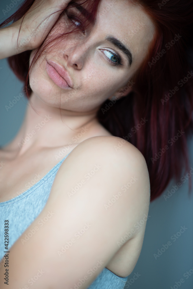 Fototapeta premium Beautiful young ginger woman with freckles. Fashion portrait of charming girl wearing casual clothes posing at home. Passion