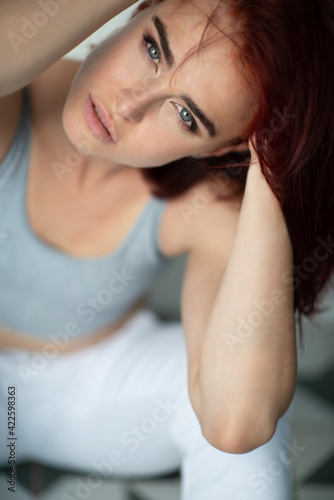 Beautiful young ginger woman with freckles. Fashion portrait of charming girl wearing casual clothes posing at home. Passion