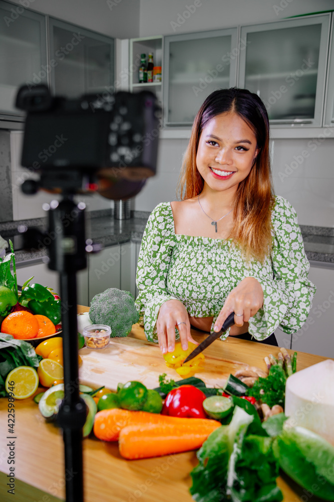 Asian woman blogger or content creator cooking and recording video camera. showing healthy food while recording with camera at kitchen. Asian woman blogger or content creator cooking and recording video camera. showing healthy food while recording with camera at kitchen.
