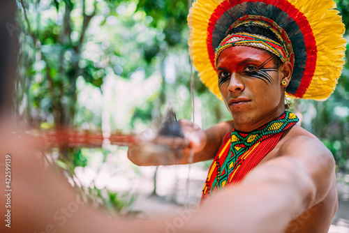 Indian from the Pataxó tribe using a bow and arrow. Brazilian Indian with feather headdress and necklace