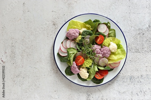 Raw vegetable salad with colorful cauliflower, lettuce, radish and tomato. Selective focus