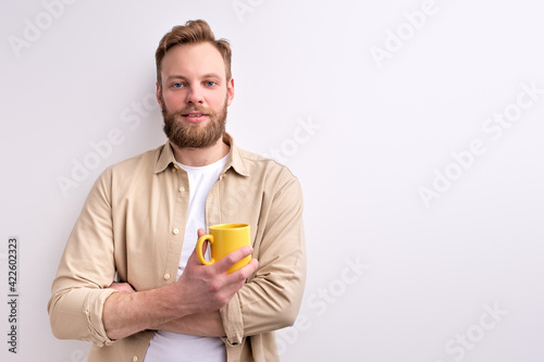 Young Caucasian Man In Casual Wear Posing At Camera Holding Yellow Mug In Hands