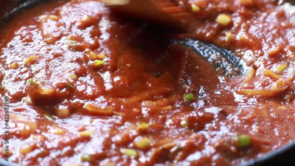 stirring a tomato sauce on the stove top stirring a tomato sauce on the stove top