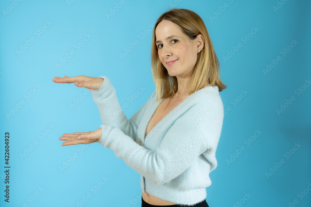 Young woman over isolated background holding something with both hands, product presentation. Young woman over isolated background holding something with both hands, product presentation.