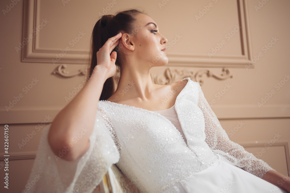 Beautiful fashion young bride in beige studioo interior before wedding ceremony in church Beautiful fashion young bride in beige studioo interior before wedding ceremony in church