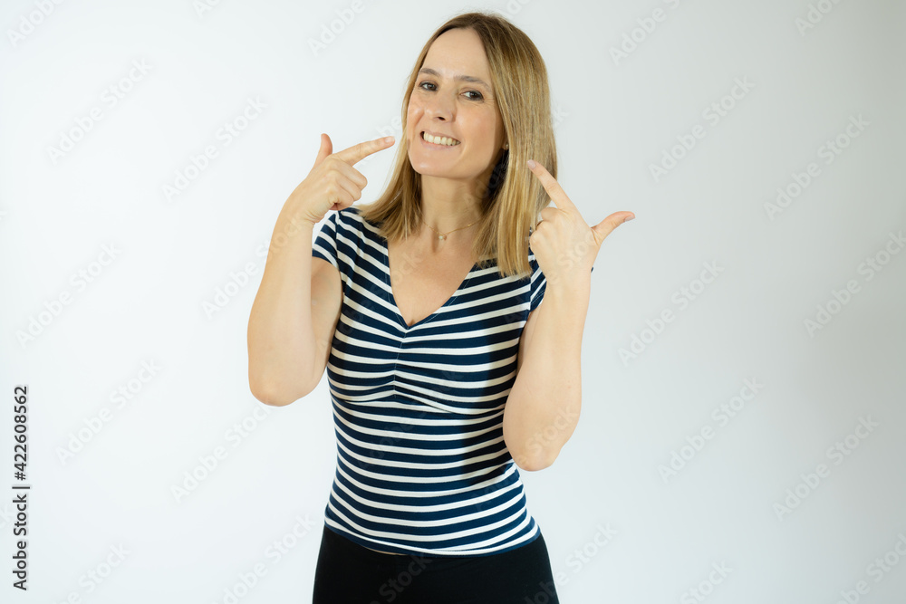 Young beautiful woman wearing striped t-shirt standing over white isolated background smiling cheerful showing and pointing with fingers teeth and mouth. Dental health concept. Young beautiful woman wearing striped t-shirt standing over white isolated background smiling cheerful showing and pointing with fingers teeth and mouth. Dental health concept.