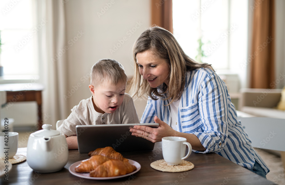 Single mother with down syndrome child at home, using tablet. Single mother with down syndrome child at home, using tablet.