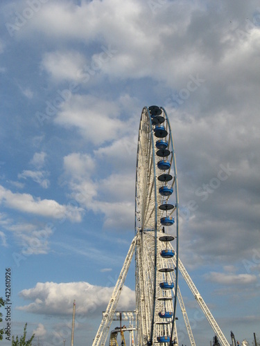 a big wheel at a fair in antwerp with a blue sky with clouds in the background © Angelique