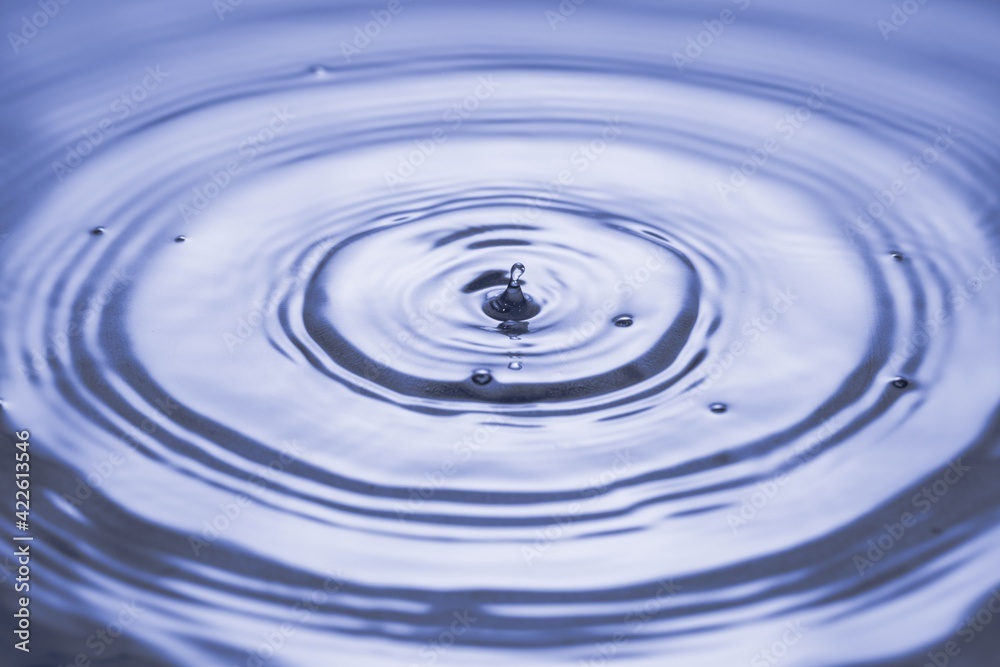 View macro of drops making circles on blue water surface isolated on background. View macro of drops making circles on blue water surface isolated on background.