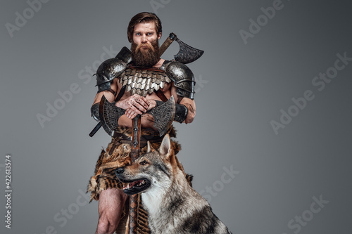 Grimy barbaric viking with nude body posing with beautiful wolf