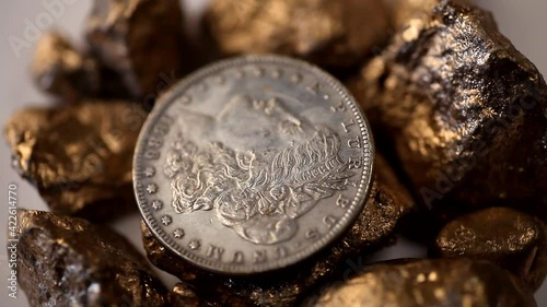American silver one dollar coin and Golden nuggets rotating on white background.