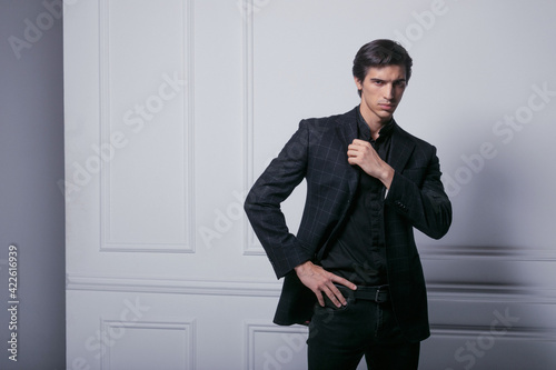 Closeup portrait of a business man wear black elegant suit portrait against a neoclasic wall, looking at the side. photo