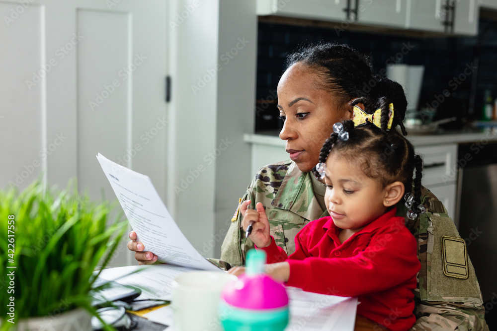 Focused military woman working from home at laptop and paying bills Focused military woman working from home at laptop and paying bills