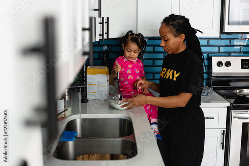 Black army mother cooks breakfast in kitchen with daughter