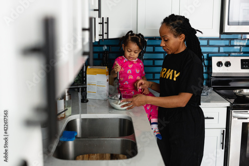 Black army mother cooks breakfast in kitchen with daughter photo