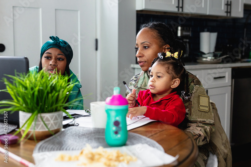 Black mother and daughter paying bills at home, soldier