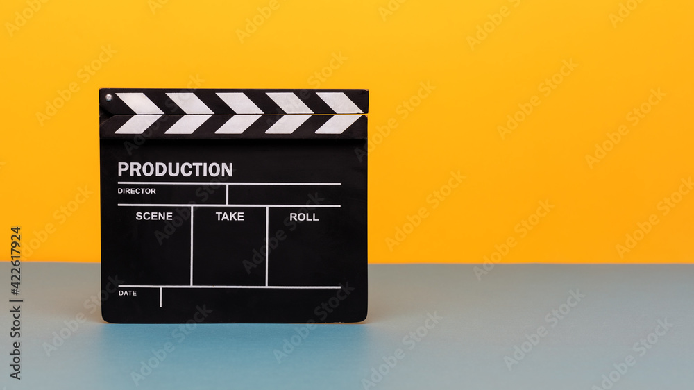 Naklejka premium Filmmaker profession. Clapperboard on yellow and teal blue background