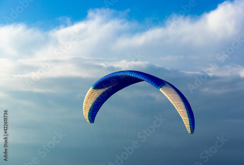 Paragliding in the sky. Paraglider tandem flying over the sea with mountains at sunset