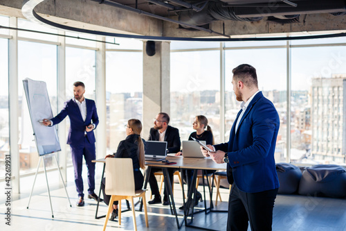 Business people working together in a modern office with cityscape view. The director tells the staff about new technologies. Office work concept